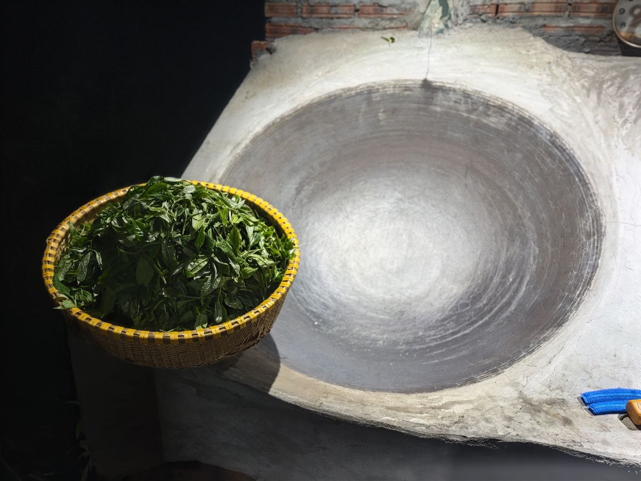 Rổ trà tươi vừa hái đặt bên chảo sao trà